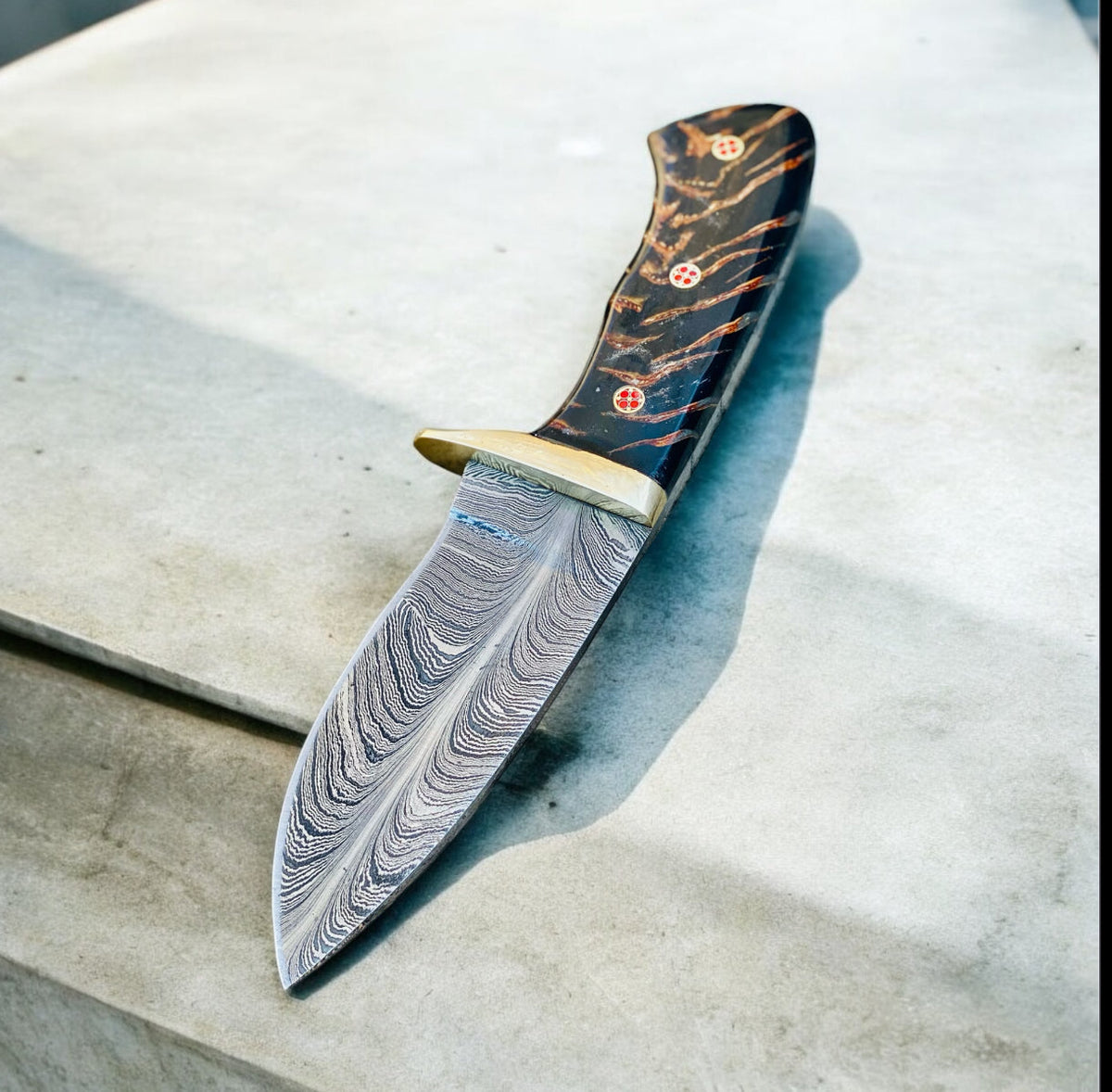 Damascus hunting knife with pine cone resin handle, brass guard, and leather sheath