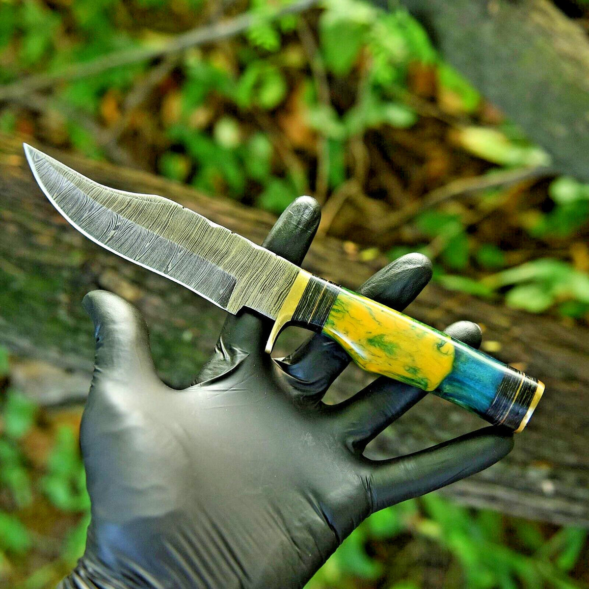 Damascus hunting knife with a resin pakkawood handle, brass guard and leather sheath