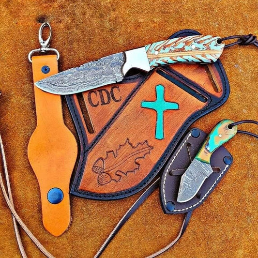 Damascus belt knife with a pine cone handle and steel bolster beside a leather sheath