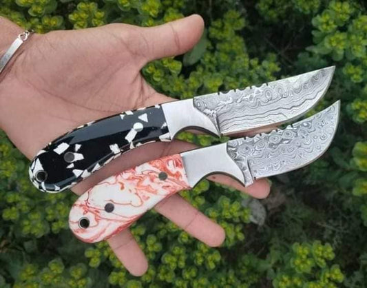 Damascus bull cutter knife with a resin handle and steel bolster beside a leather sheath