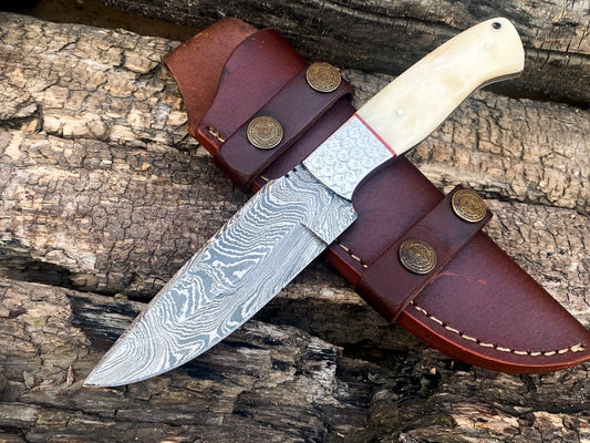 Damascus bushcraft knife with a cream camel bone handle and steel bolster