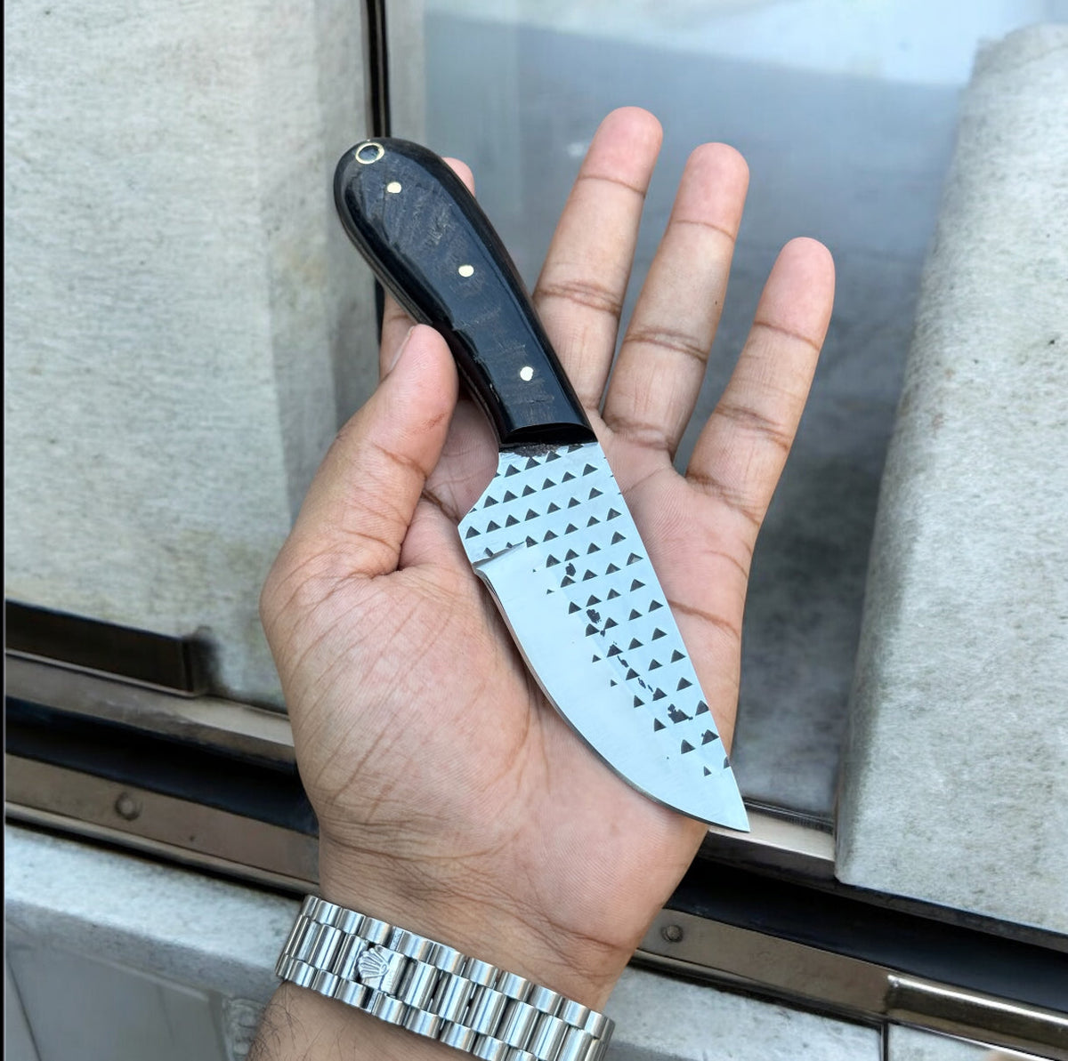 Rasp steel cowboy knife with a resin handle beside a brown leather belt sheath