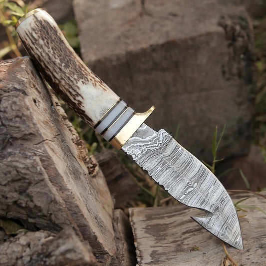 Damascus guthook skinning knife with stag horn handle, brass guard and leather sheath